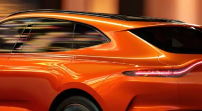 Side view of in motion orange Aston Martin DBX707