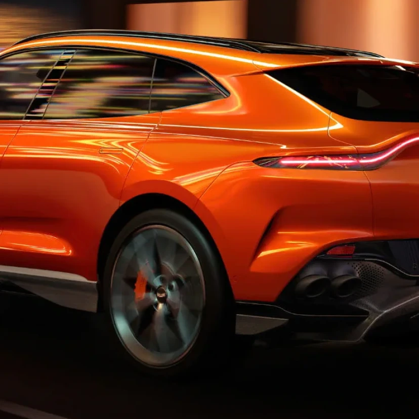 Side view of in motion orange Aston Martin DBX707