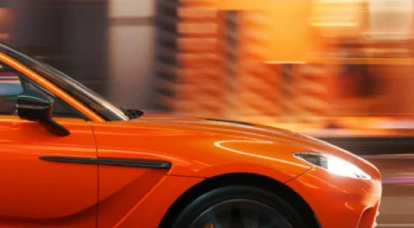 Side view of in motion orange Aston Martin DBX707