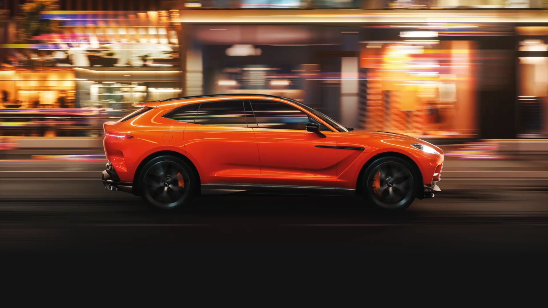 Side view of in motion orange Aston Martin DBX707