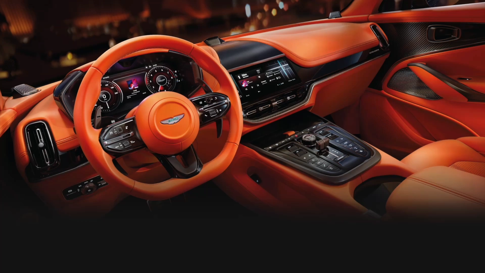 Interior view of driver's side in an orange Aston Martin DBX707